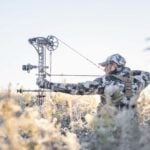 bowhunter at full draw in a frosty field