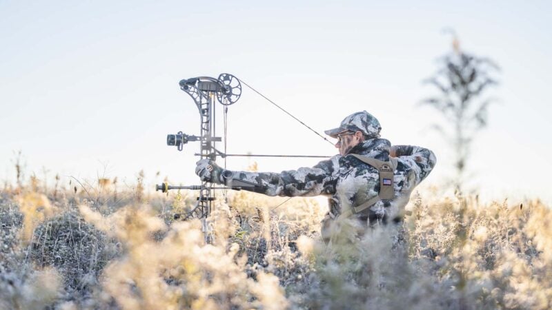 bowhunter at full draw in a frosty field