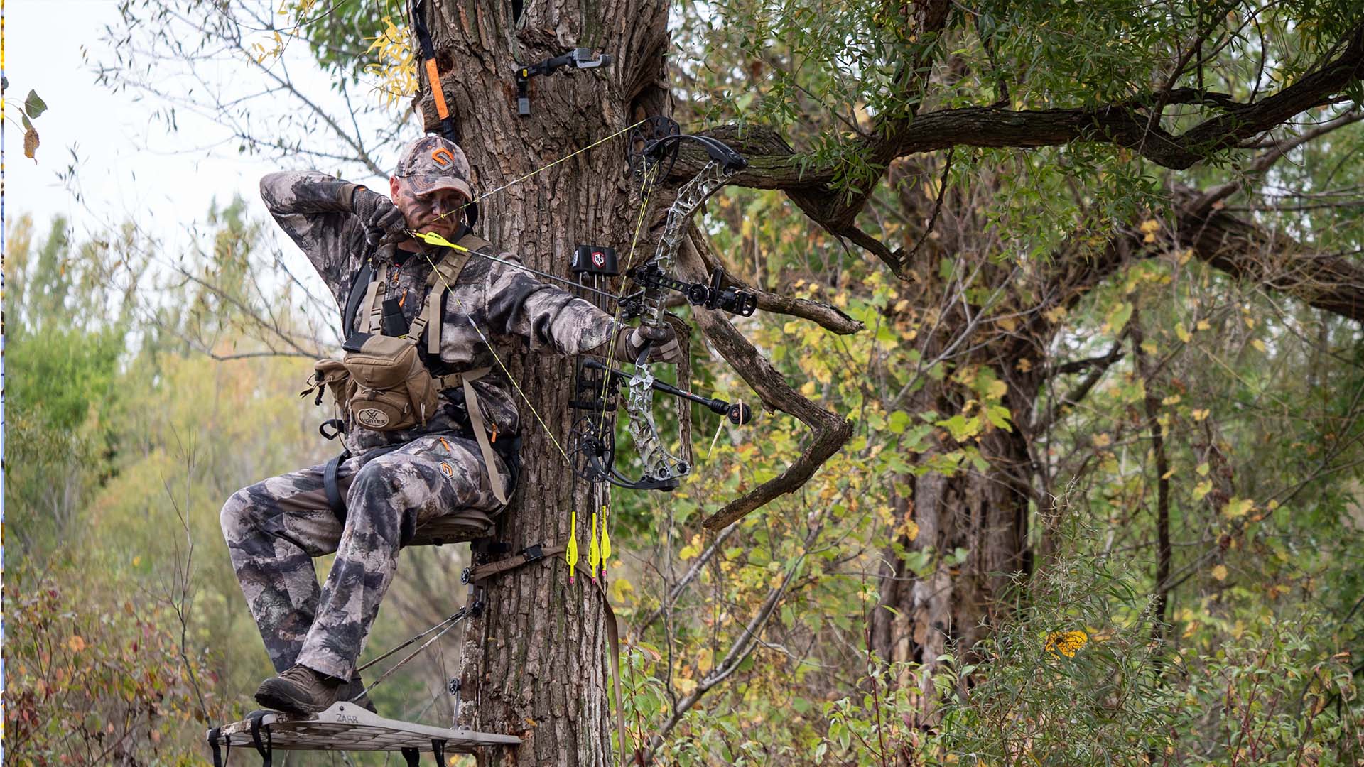 Bowhunter at full draw sitting in treestand