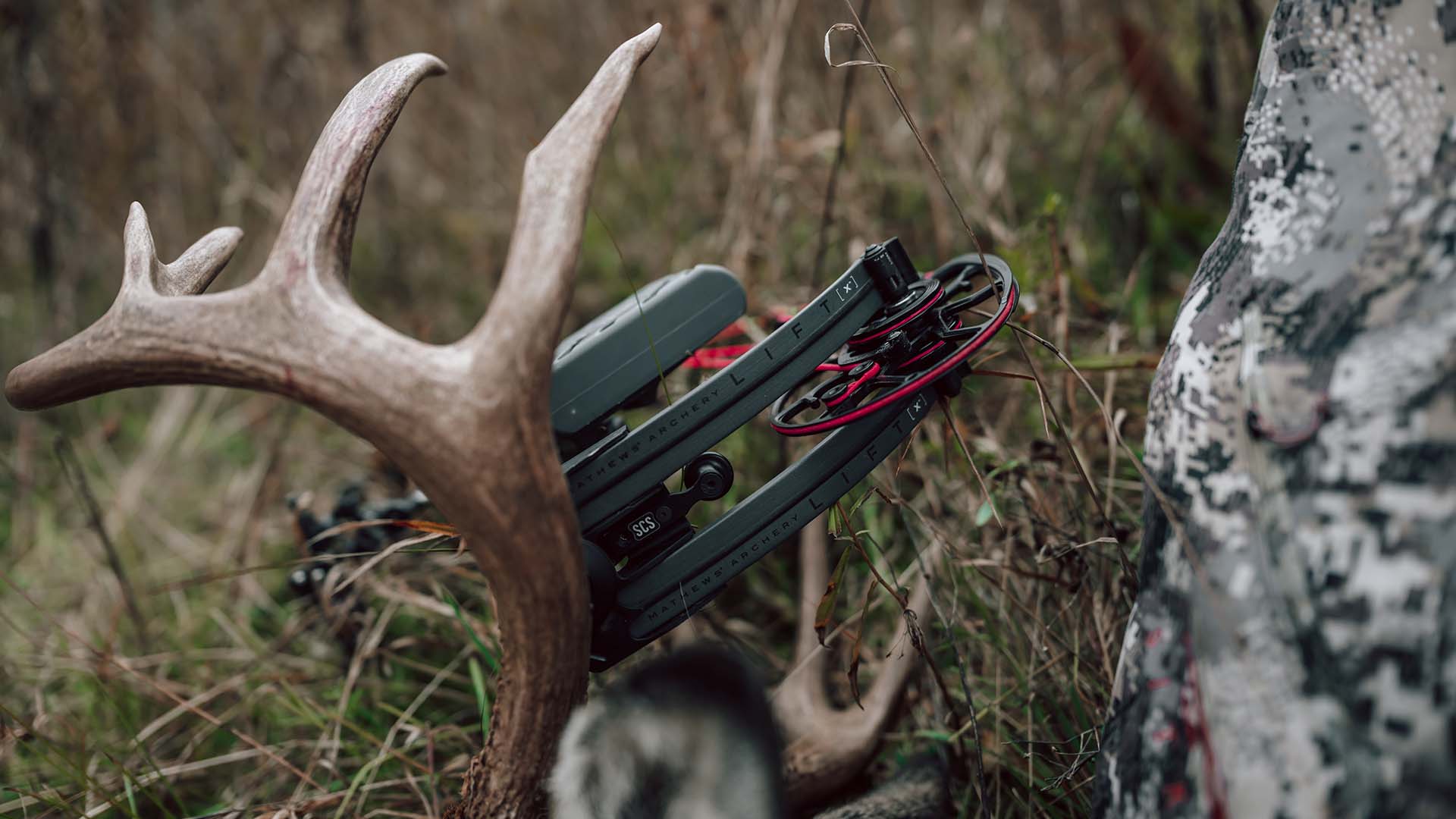 Mathews Lift X bow in Shale color with a bright red string sitting on a large whitetail buck.